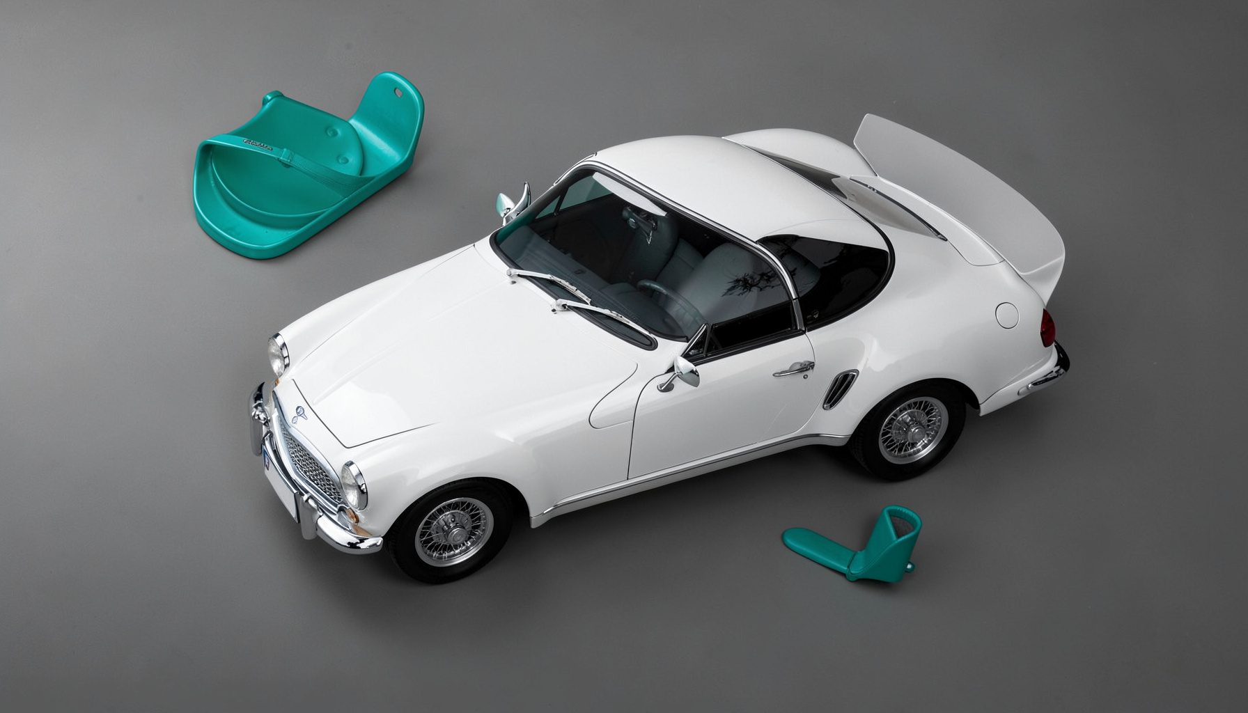 Coupé quatre portes blanc nacré, ligne de toit fuyante, calandre diamant, photographié en studio sur fond sombre.